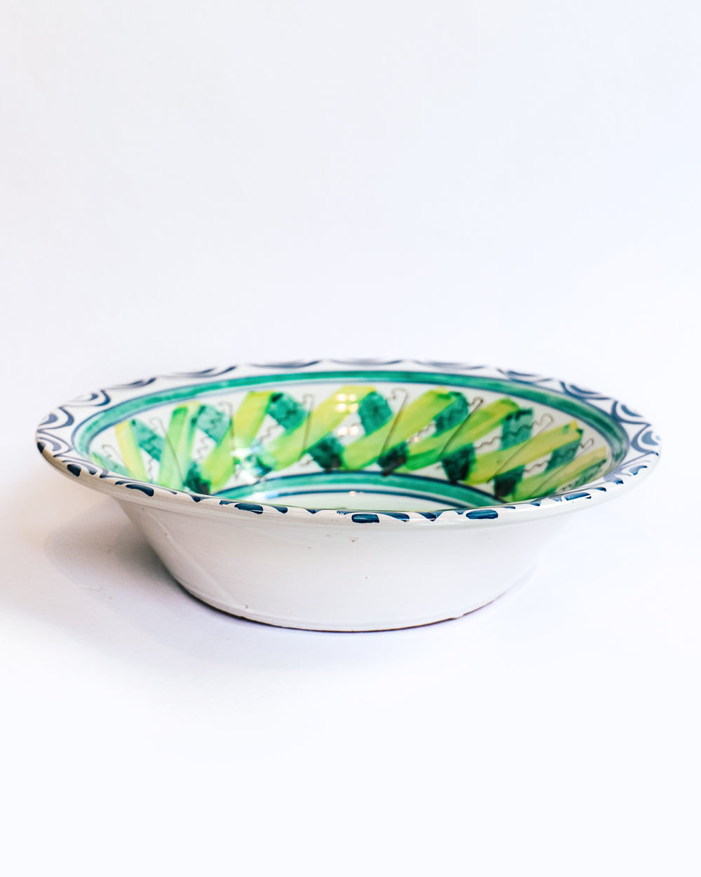 Sideview of a vintage hand-painted Italian ceramic bowl with a house and palm trees design, predominantly blue and green in color