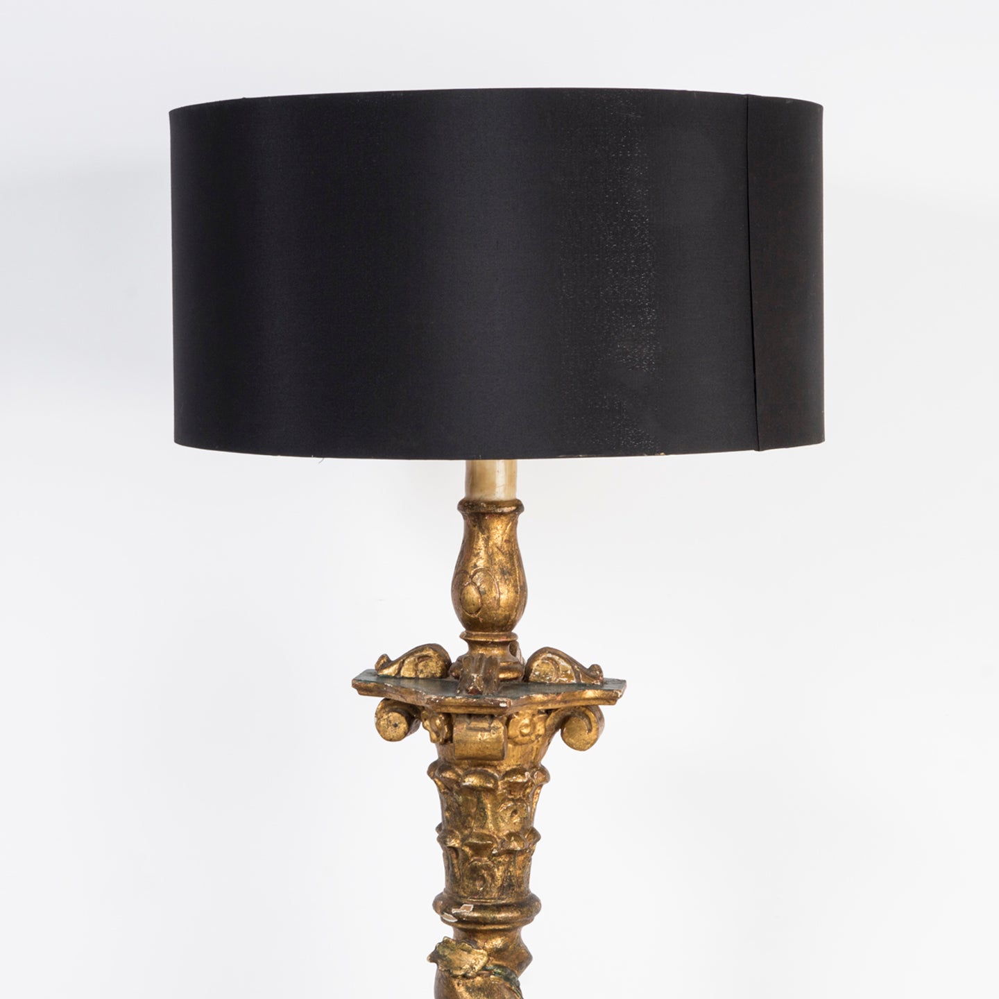 Close-up of the top part of an antique Italian gilt wood standing floor lamp with a decorative base featuring intricate grape and leaf motifs, and a contemporary black shade