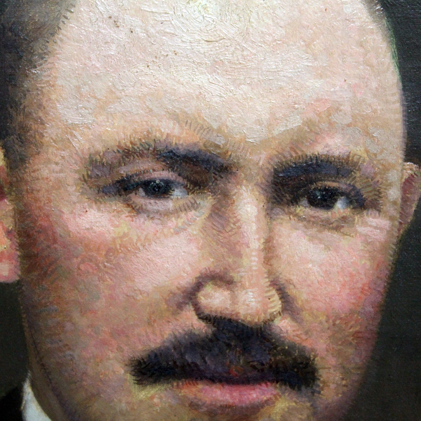 Close-up of an antique oil portrait of a gentleman with a moustache, bald head, and dark suit