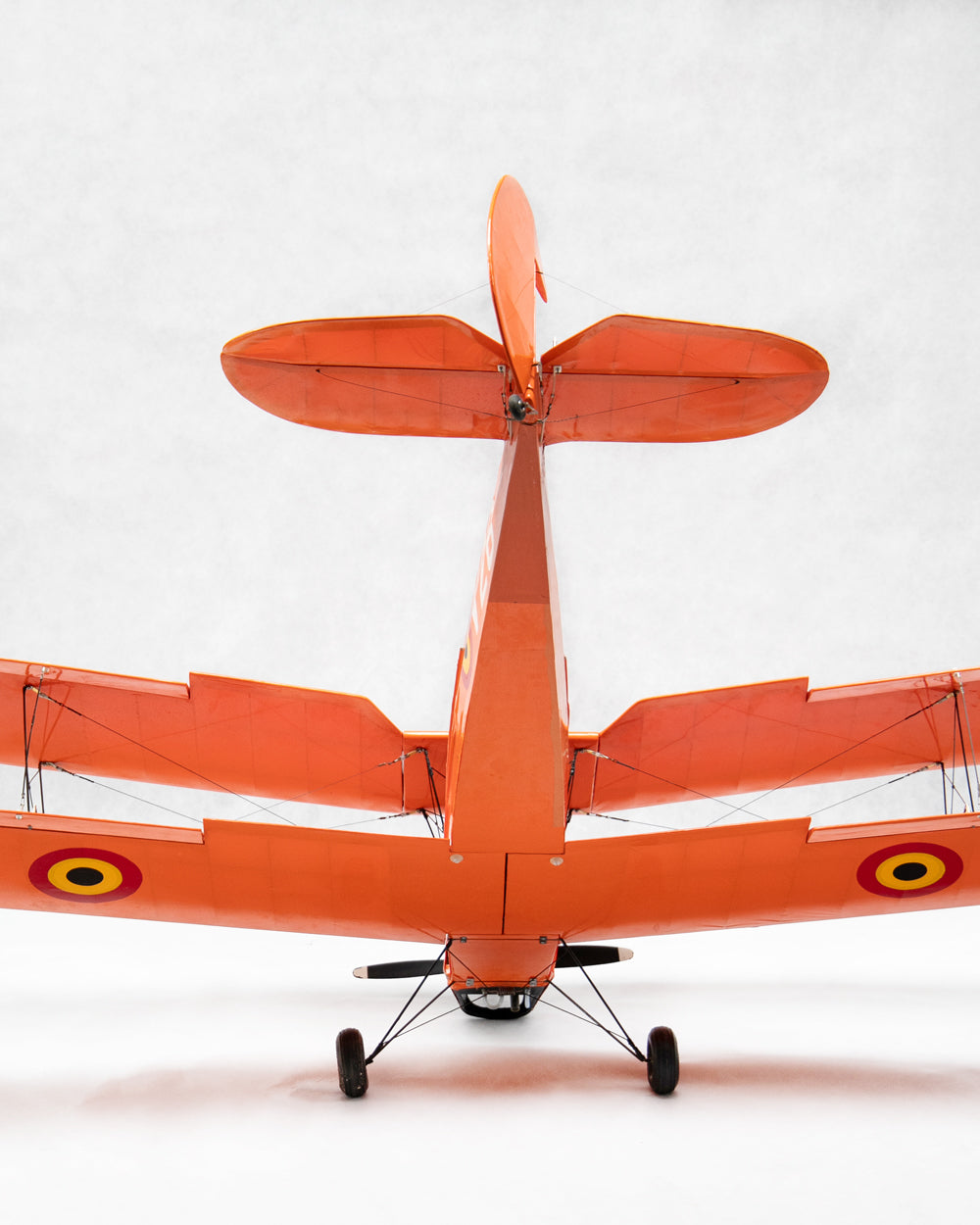 An orange model airplane viewed from the rear, set against a plain light gray background.