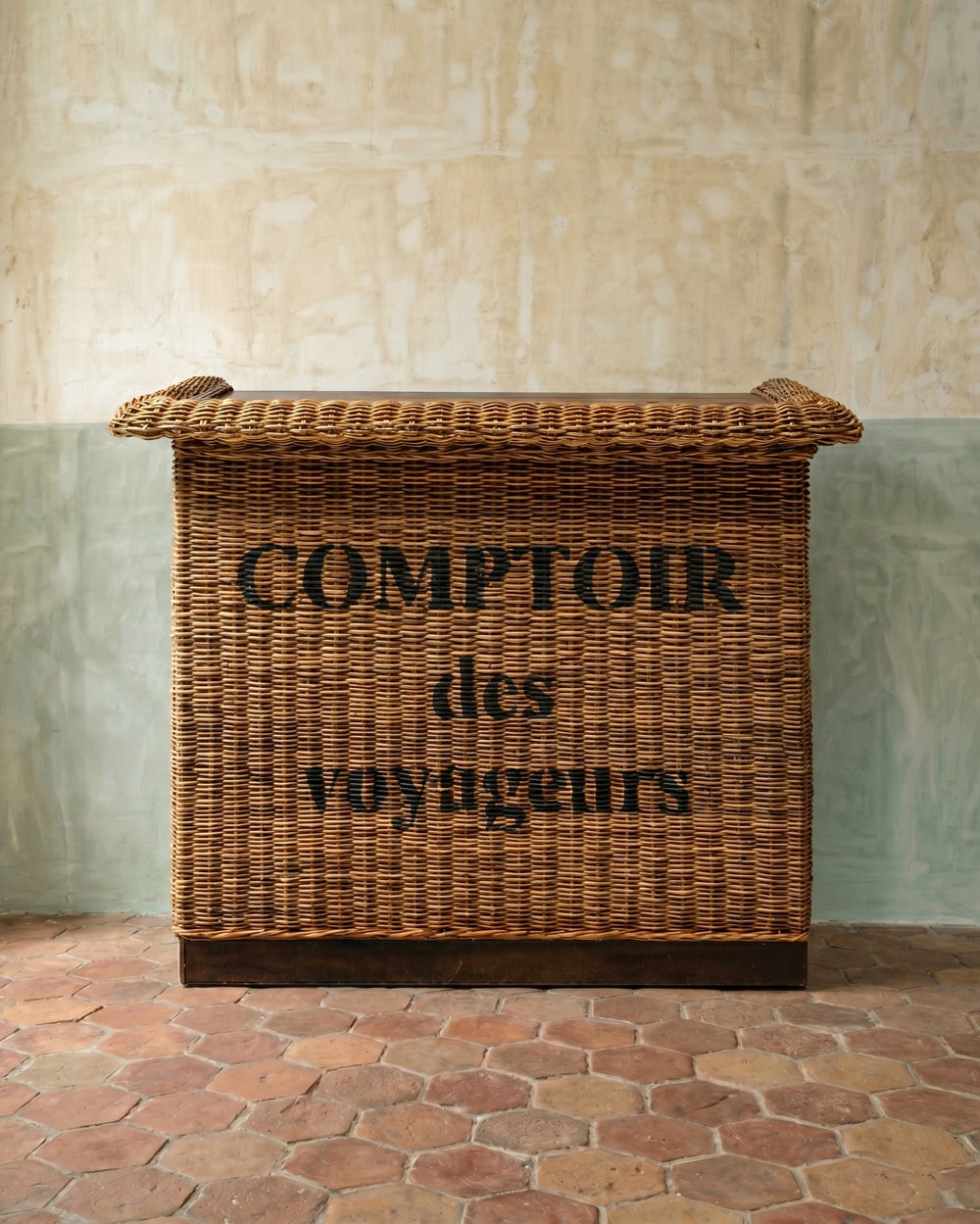 Wicker bar with 'Comptoir des Voyageurs' text against a stone wall.