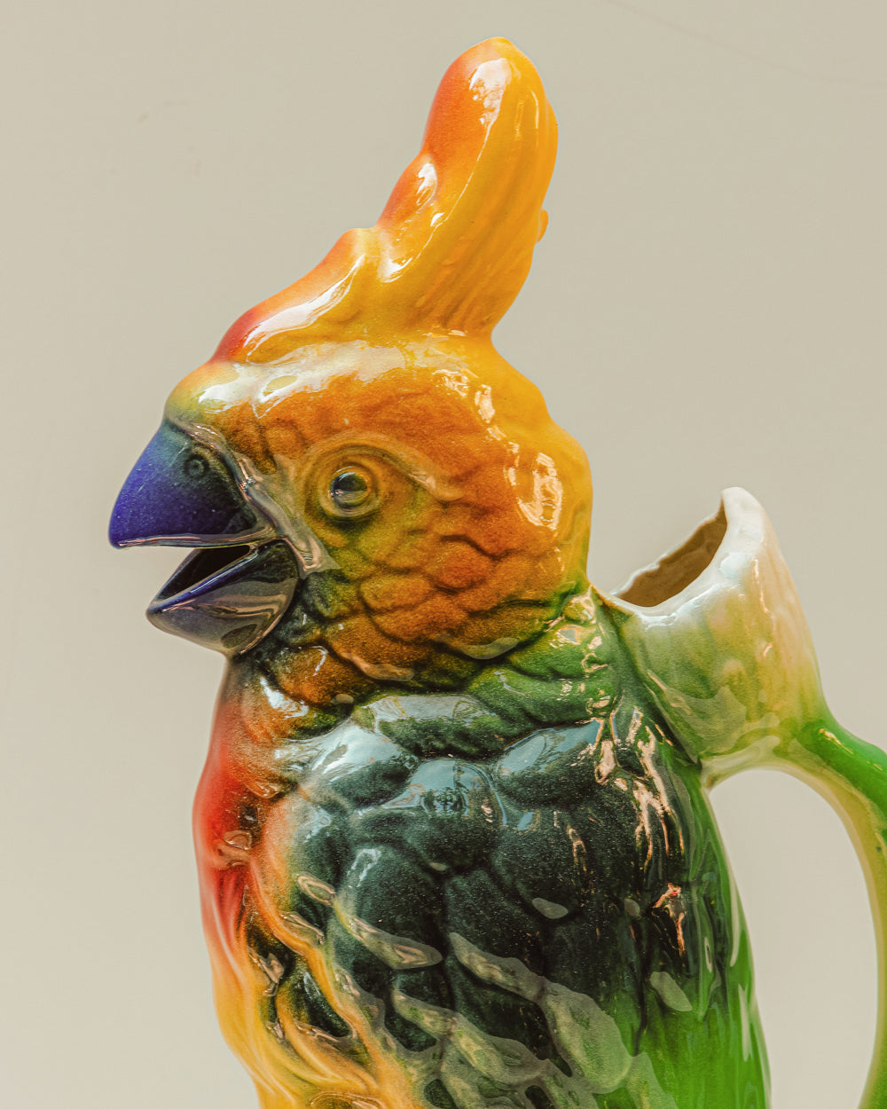 Colorful parrot-shaped ceramic pitcher on a beige background, available via Wildschut Antiques