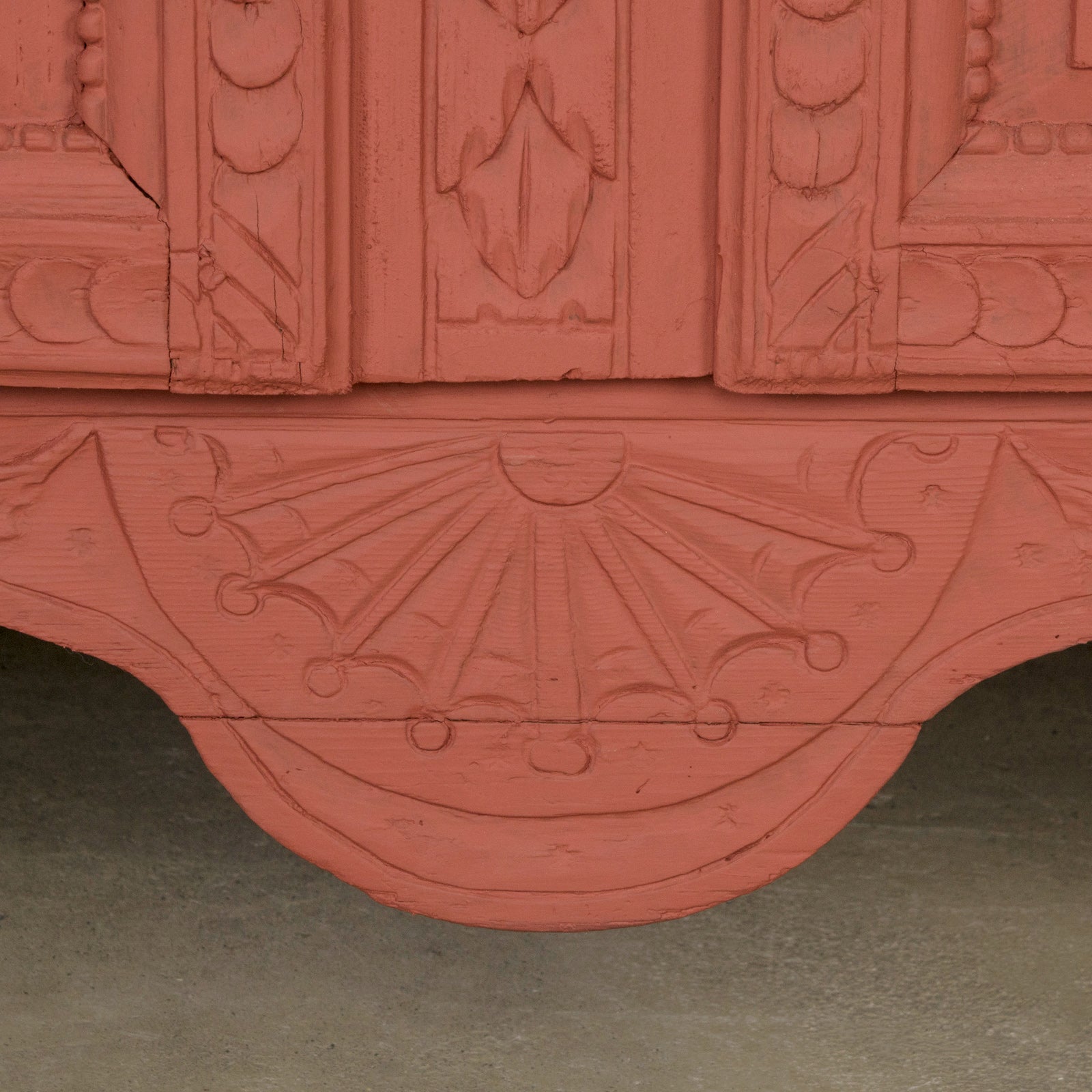 Detail of an antique French marriage armoire, painted in vibrant brick red.
