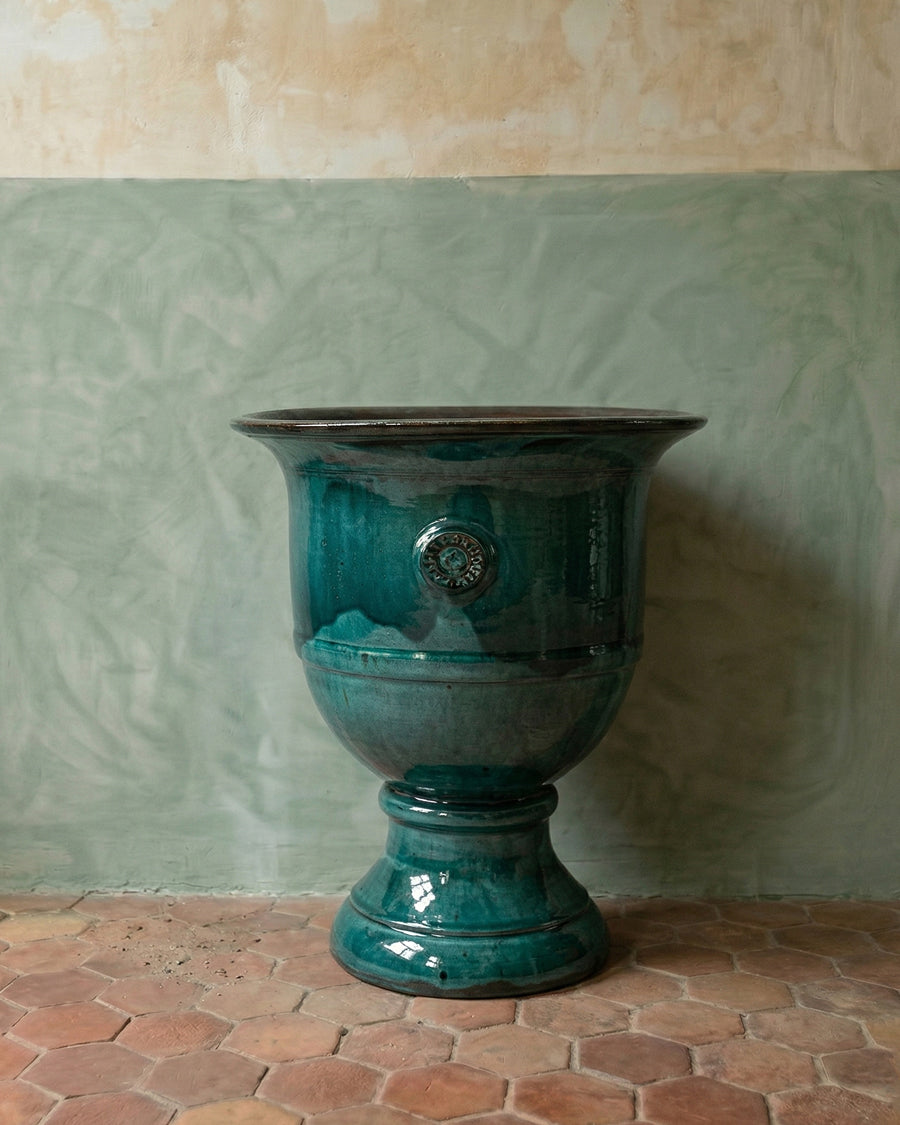 Turquoise ceramic Anduze vase, pot or jar against a textured wall with a tiled floor, available via Wildschut Antiques.