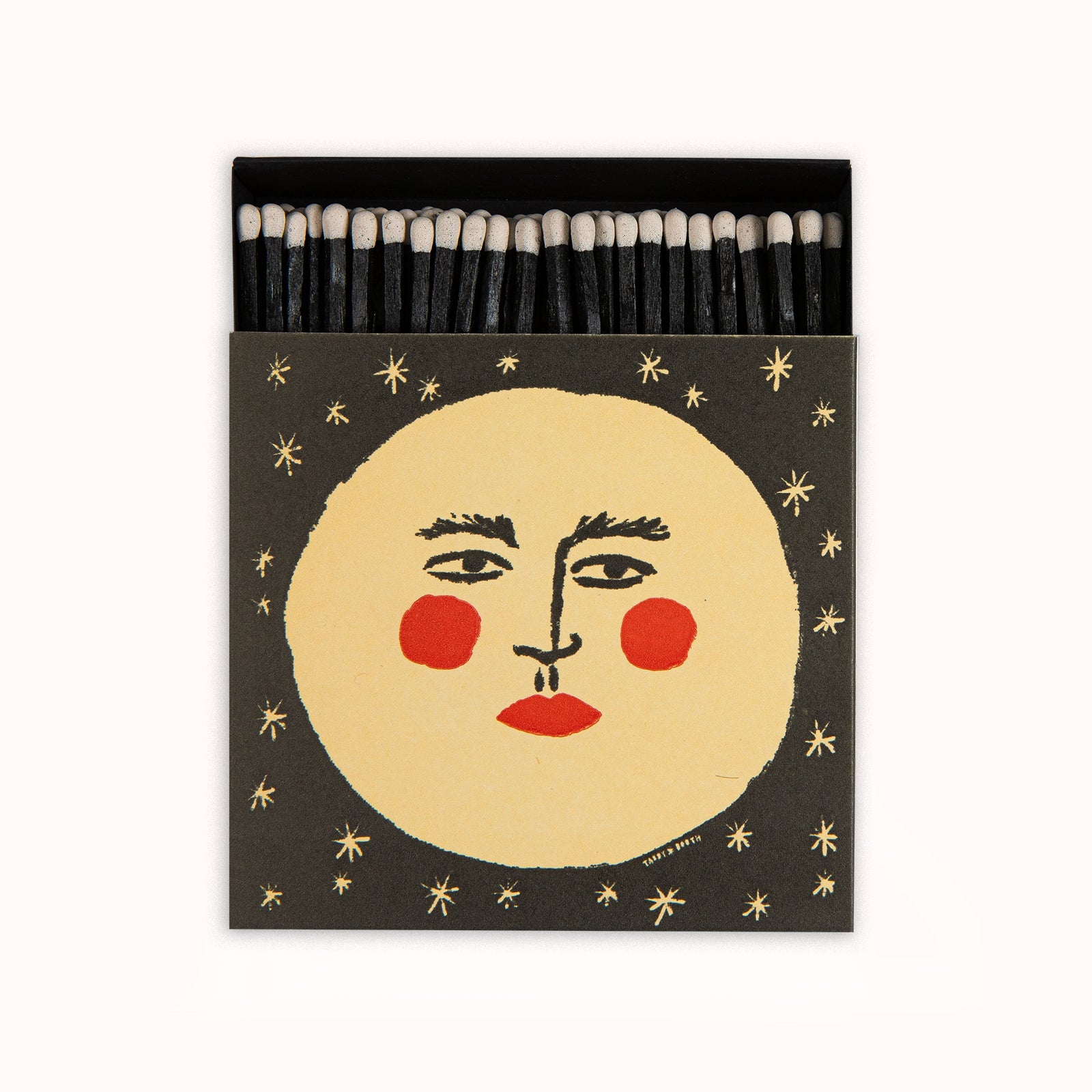 Matches in a decorative Archivist Gallery matchbox featuring a moon with a face and red cheeks, set against a black background, available at Wildschut Antiques.
