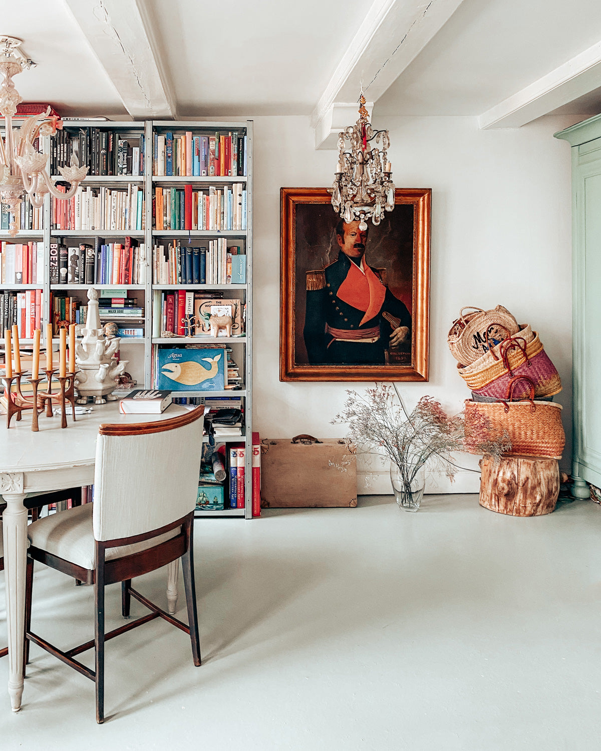 Living room with bookshelves, an antique portrait, and decorative items. A clean interior, with an antique items.