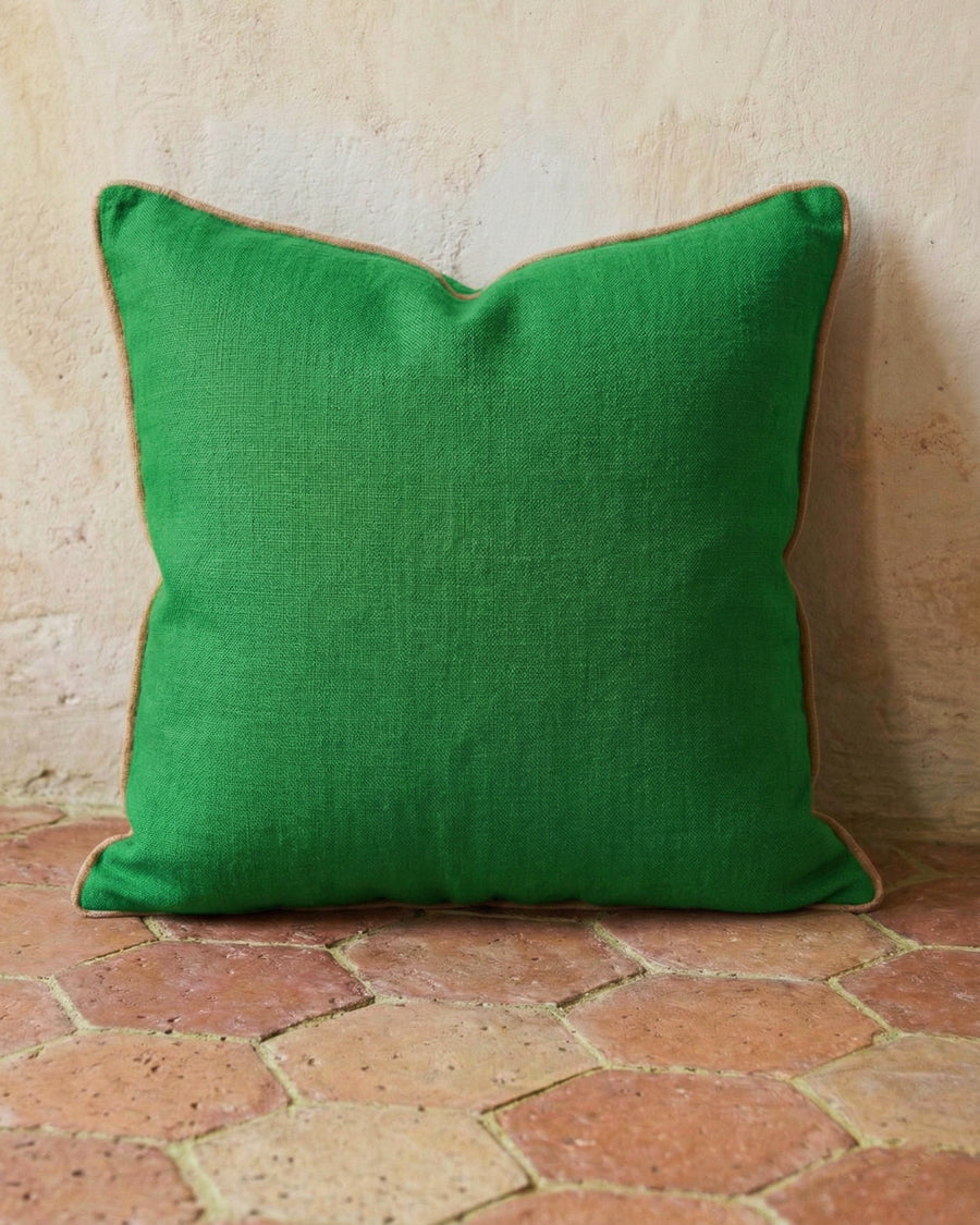 Apple green linen pillow on a textured terracotta stone floor, available via Wildschut Antiques.