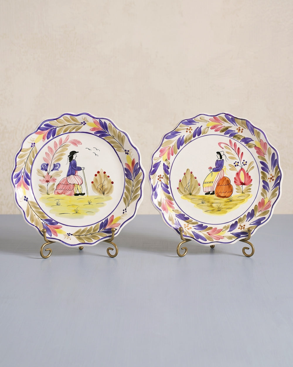 Two decorative vintage French plates with artistic hand-painted designs, displayed on a neutral background, available at Wildschut Antiques.