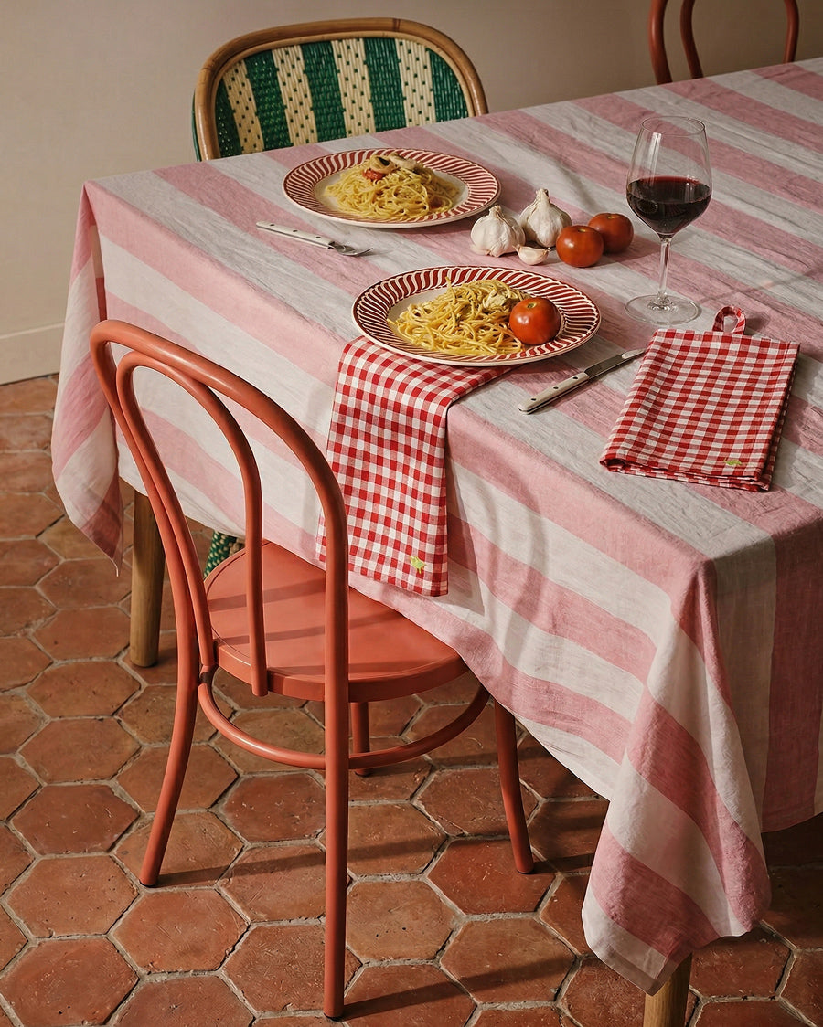 Dining table set with pasta, wine, and checkered napkins on a striped tablecloth, available via Wildschut Antiques.