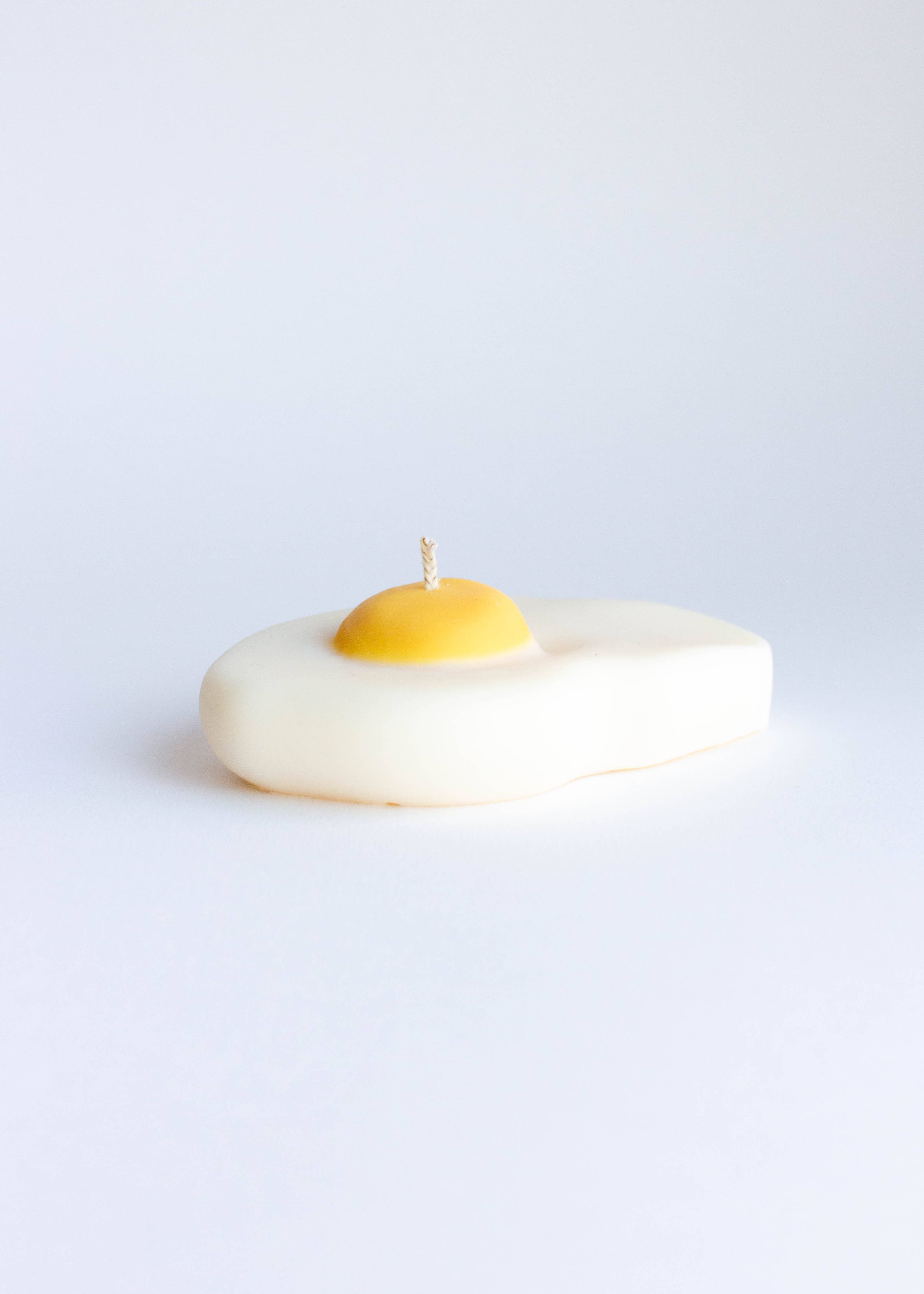 Fun candle shaped like an egg with a yellow center on a white background