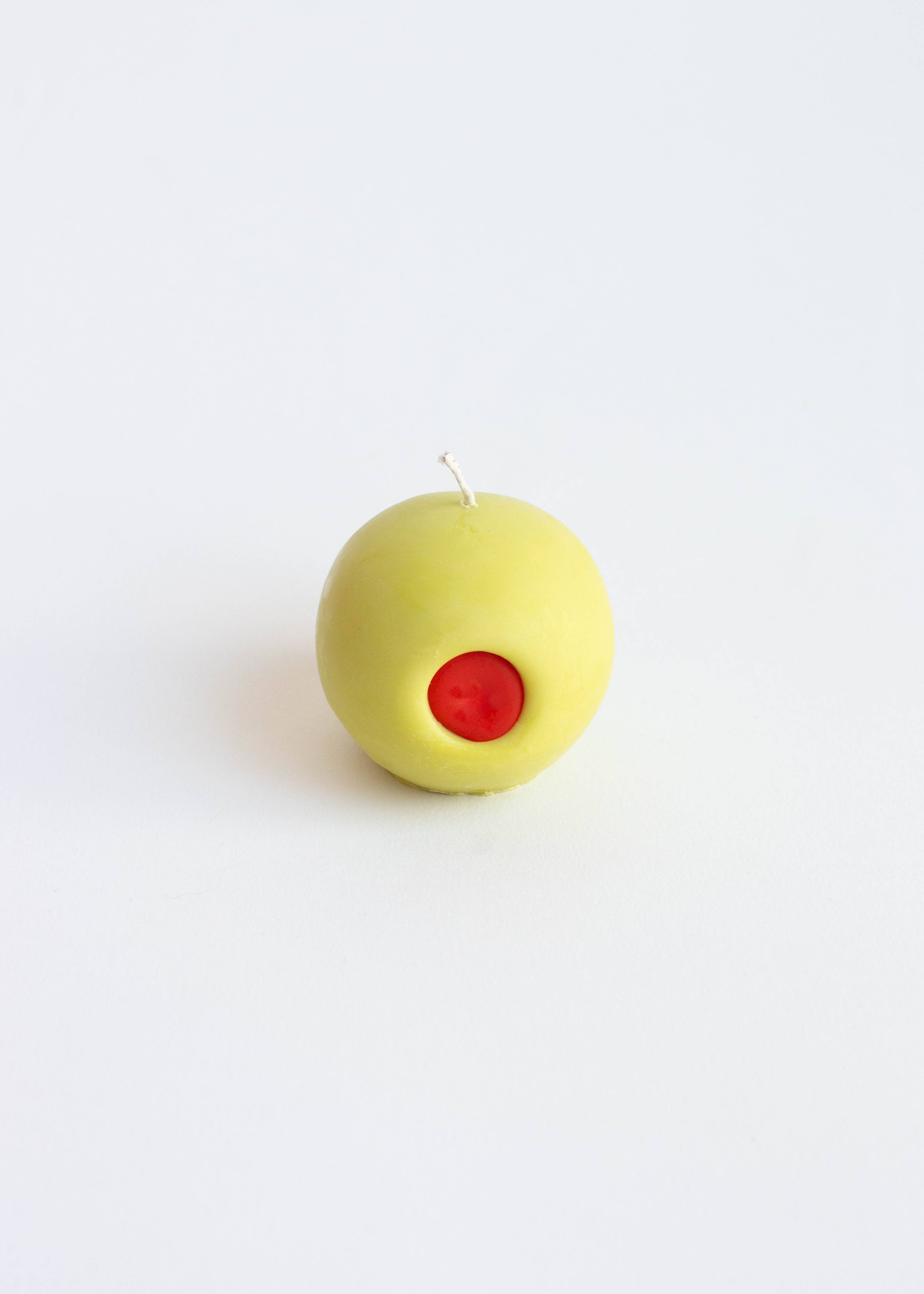 Light green olive candle with a red center on a white background