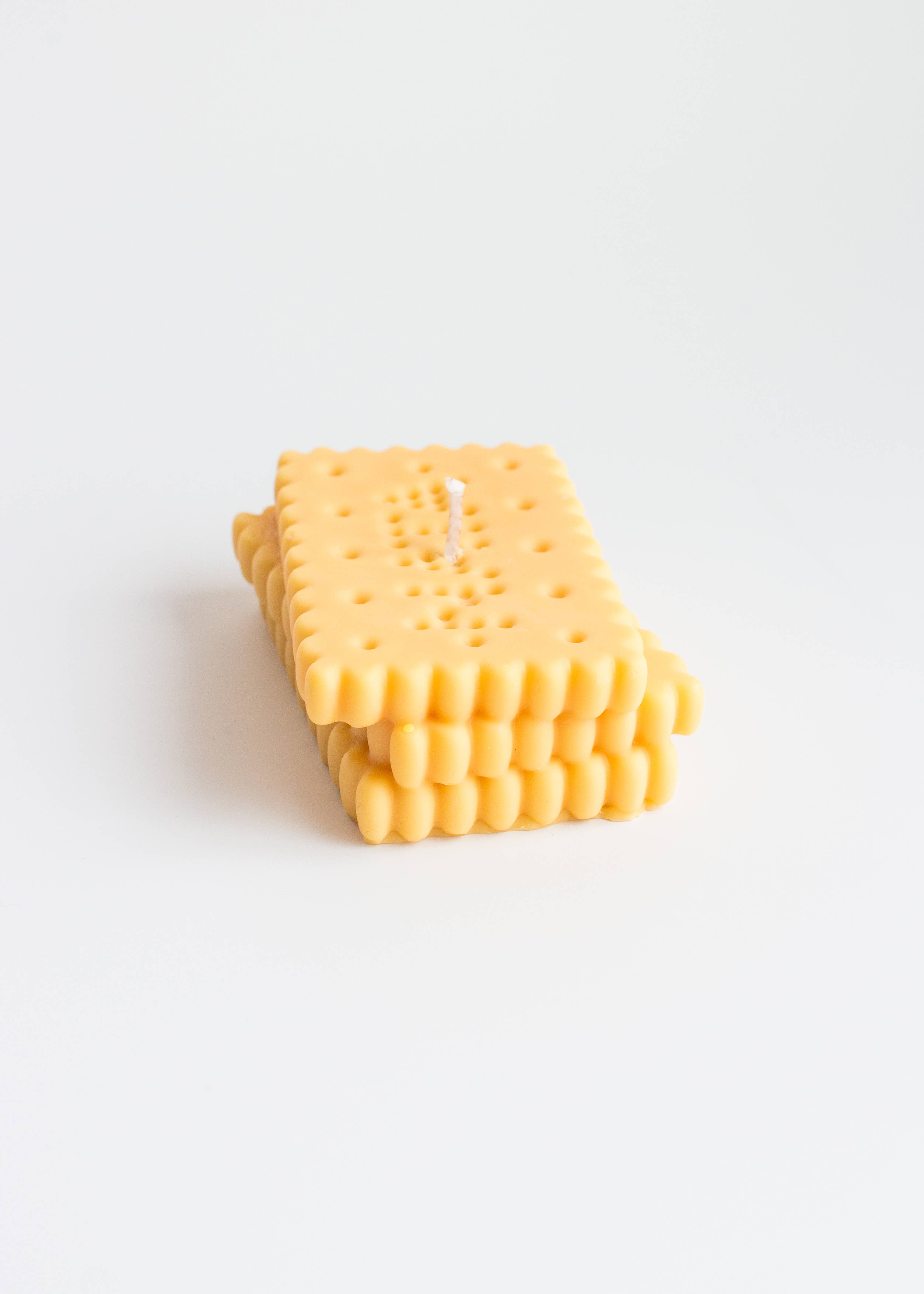 Yellow candle in the shape of a stack of 'petit beurre' biscuits on a white background