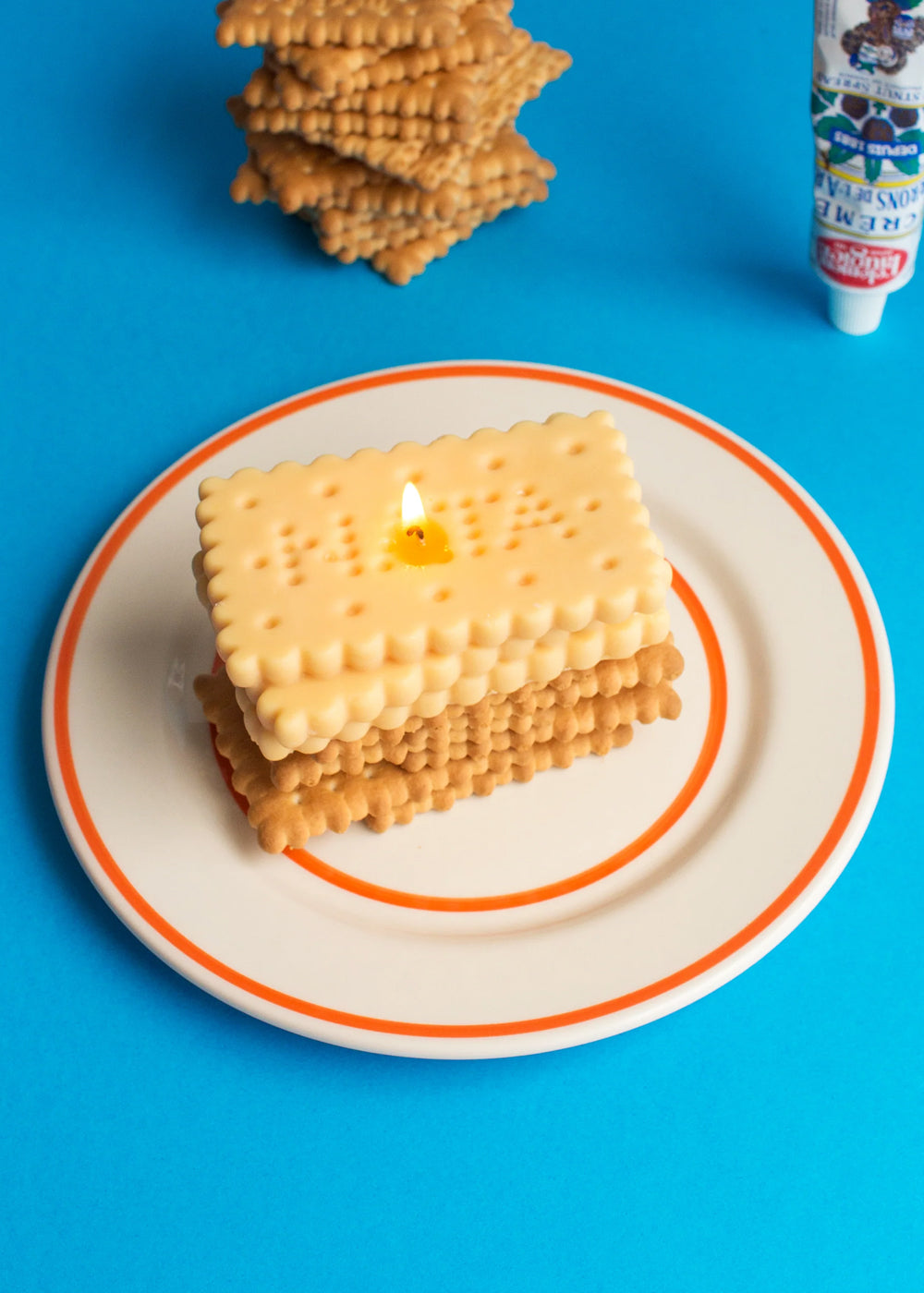 A stacked cookie candle on a plate with a blue background