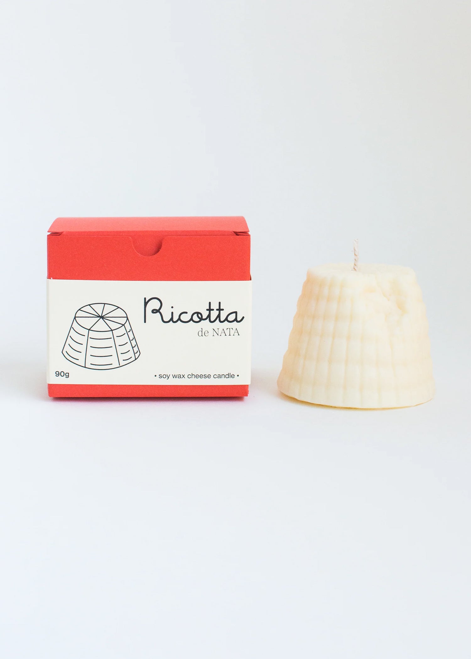 Ricotta candle with red packaging on a white background. Part of the Playful Food Candle Collection available via Wildschut Antiques Concept Store.