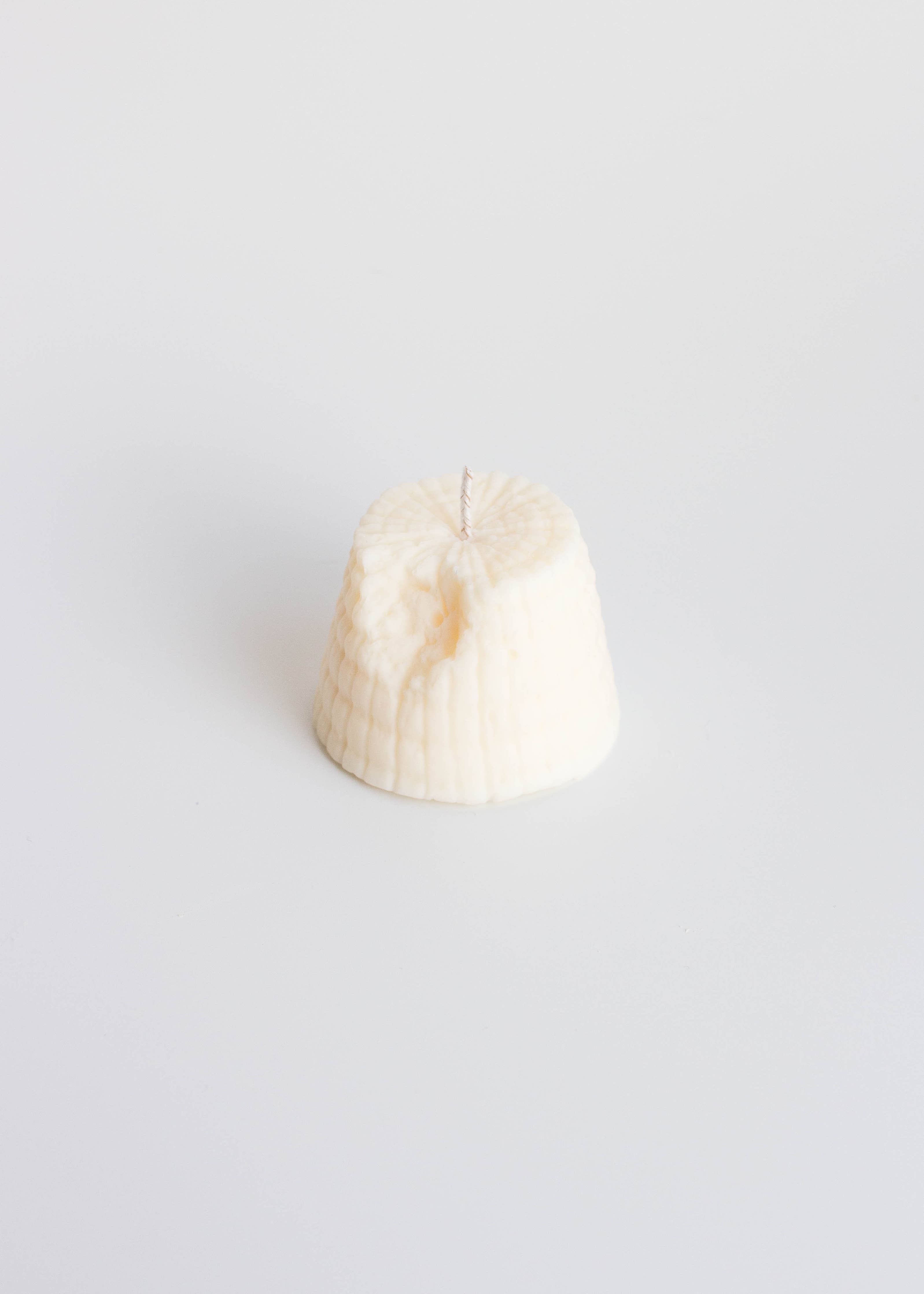 Fun Ricotta cheese shaped candle on a white background