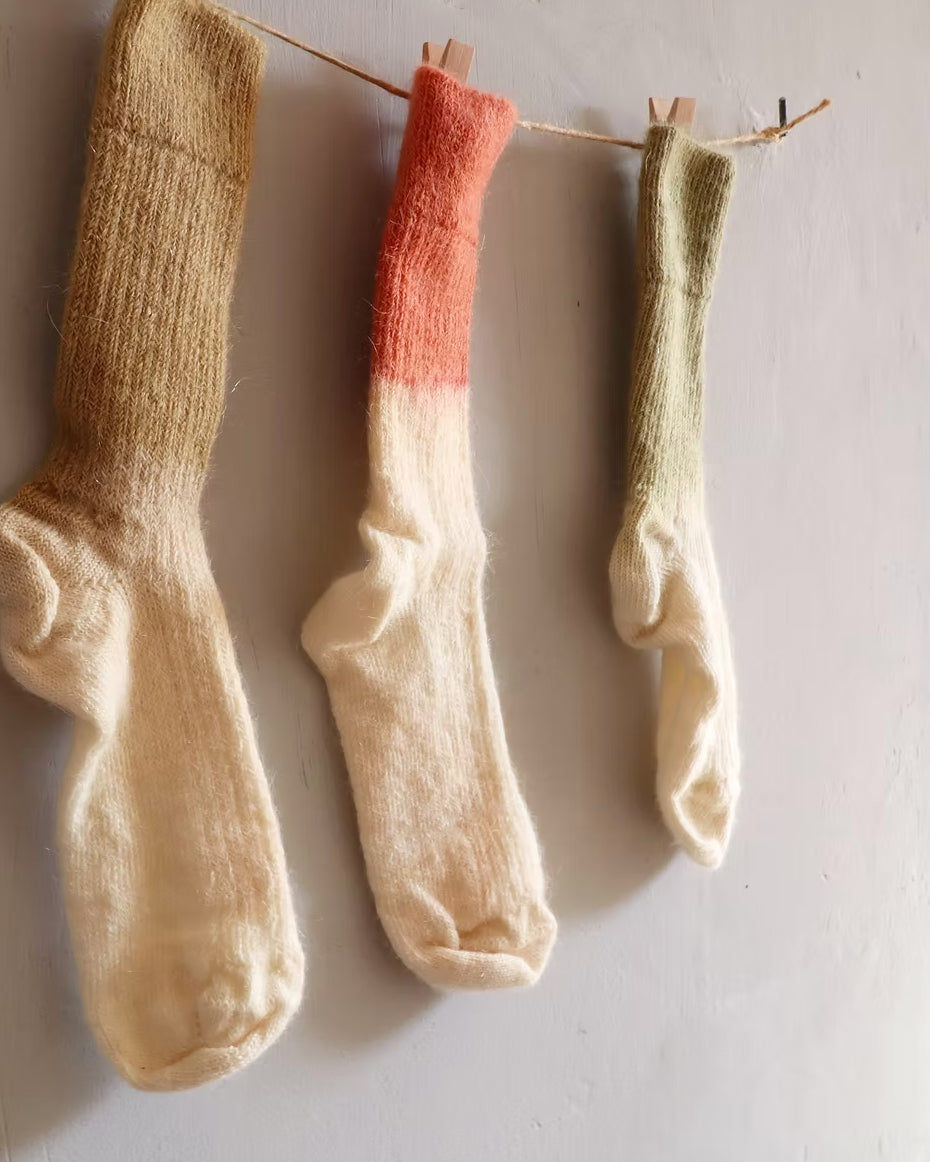 Three pairs of socks hanging on a line against a plain background