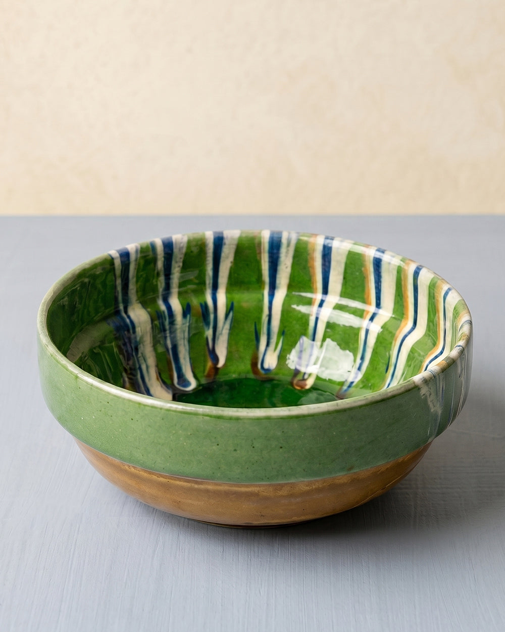 Green ceramic bowl with marble-pattern interior displayed on a grey surface, available at Wildschut Antiques.
