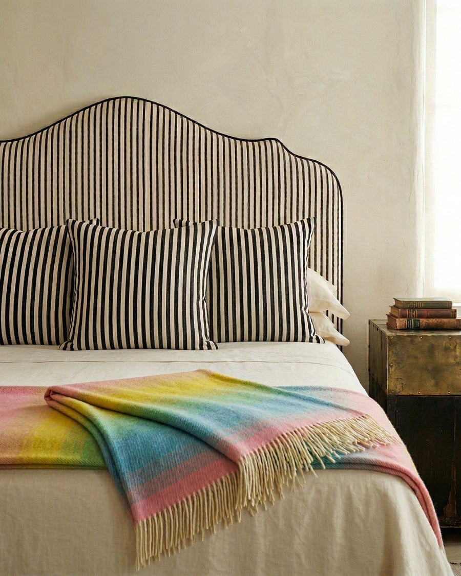 Bed with striped headboard and colorful blanket in a bedroom setting