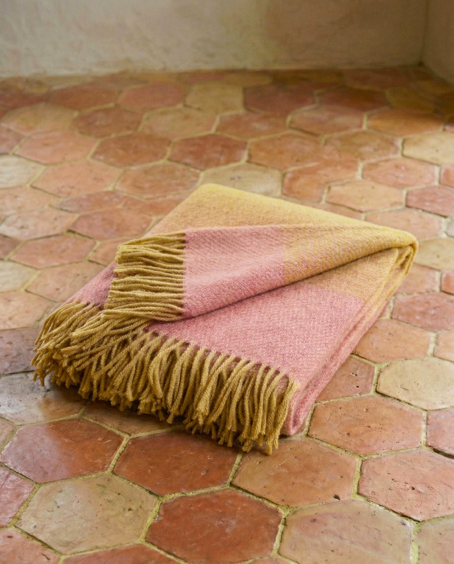 Aurora pink gradient wool blanket with fringes on a terracotta tiled floor, by Klippan, available via Wildschut Antiques.
