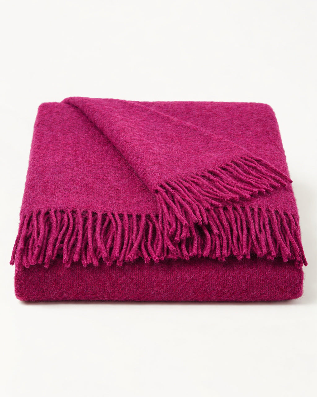 Neatly folded dark cerise pink wool blanket with fringes on a white background, by Klippan 1879, available at Wildschut Antiques.