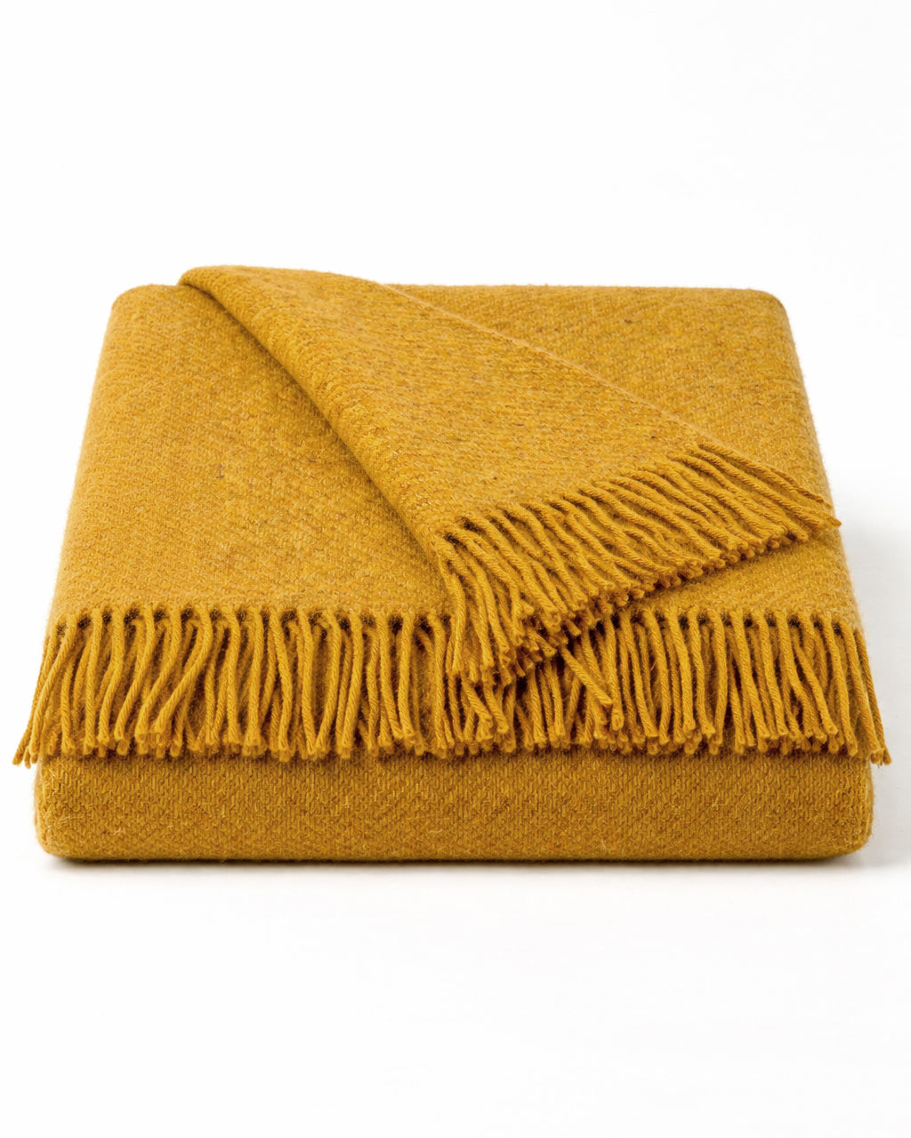 Neatly folded honey yellow wool blanket with fringes on a white background, by Klippan 1879, available at Wildschut Antiques.