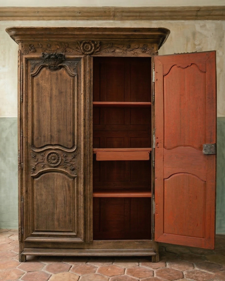 Antique French wooden marriage armoire with ornate carvings on a textured wall background, available via Wildschut Antiques.