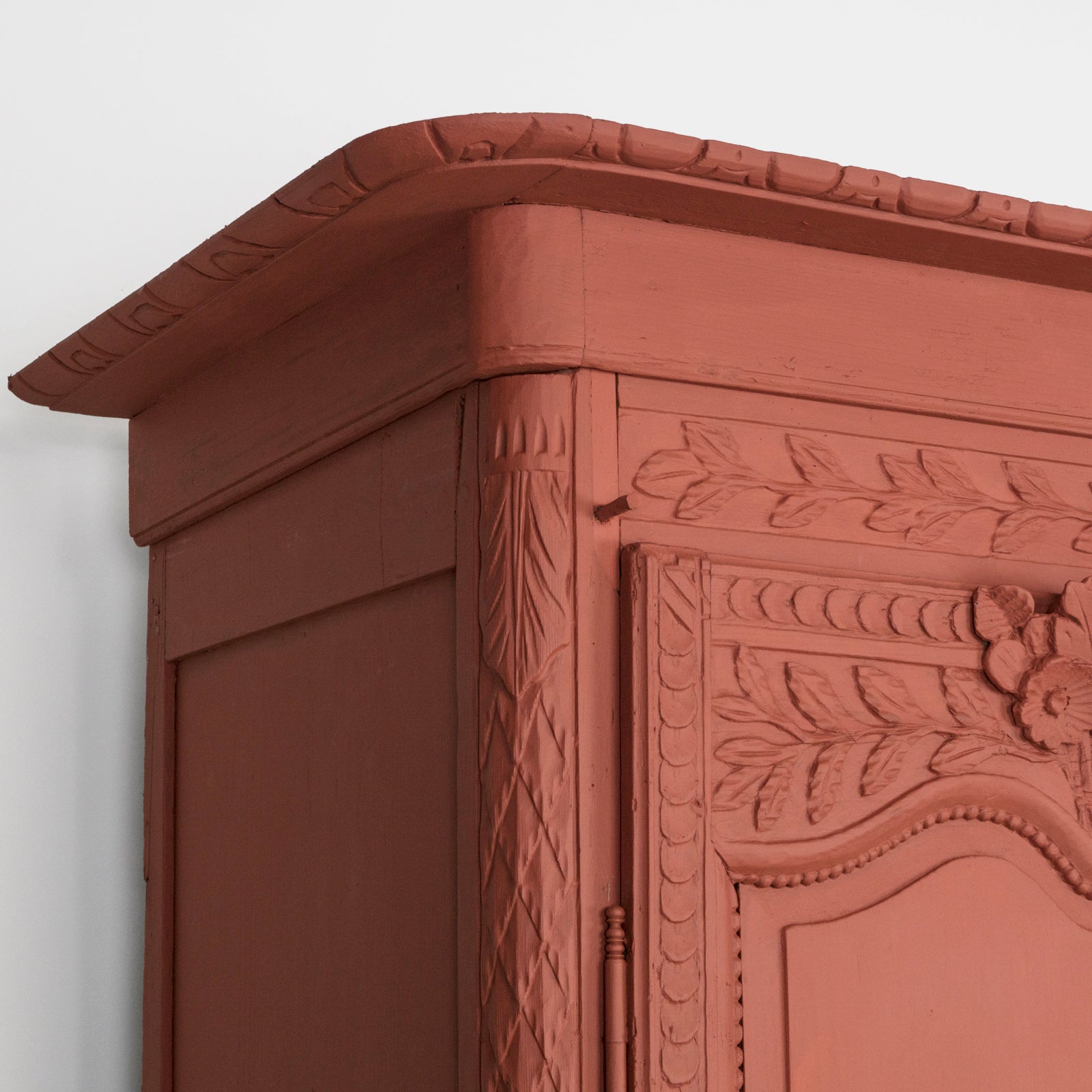 Detail of an antique French marriage armoire, painted in vibrant brick red.