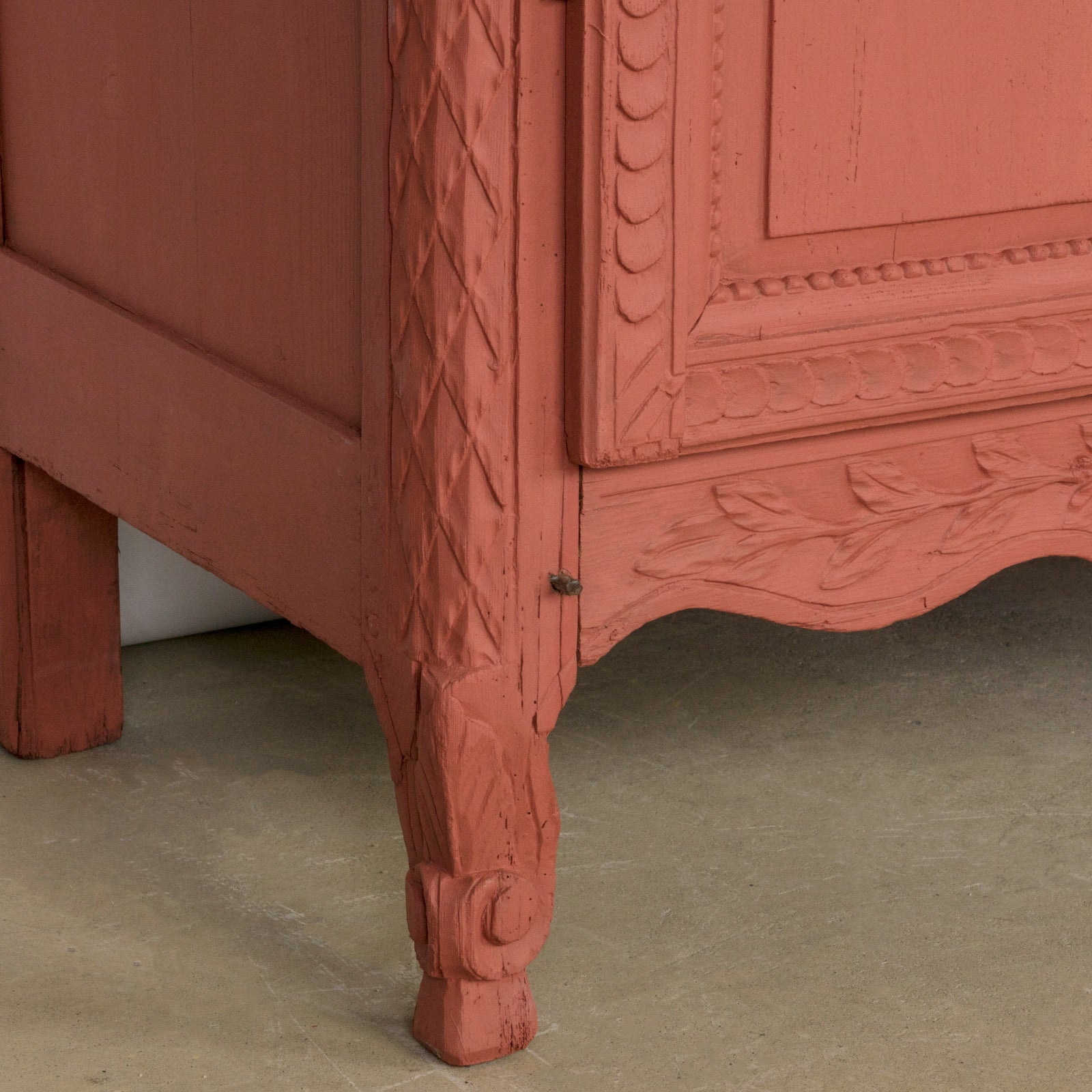 Detail of an antique French marriage armoire, painted in vibrant brick red.