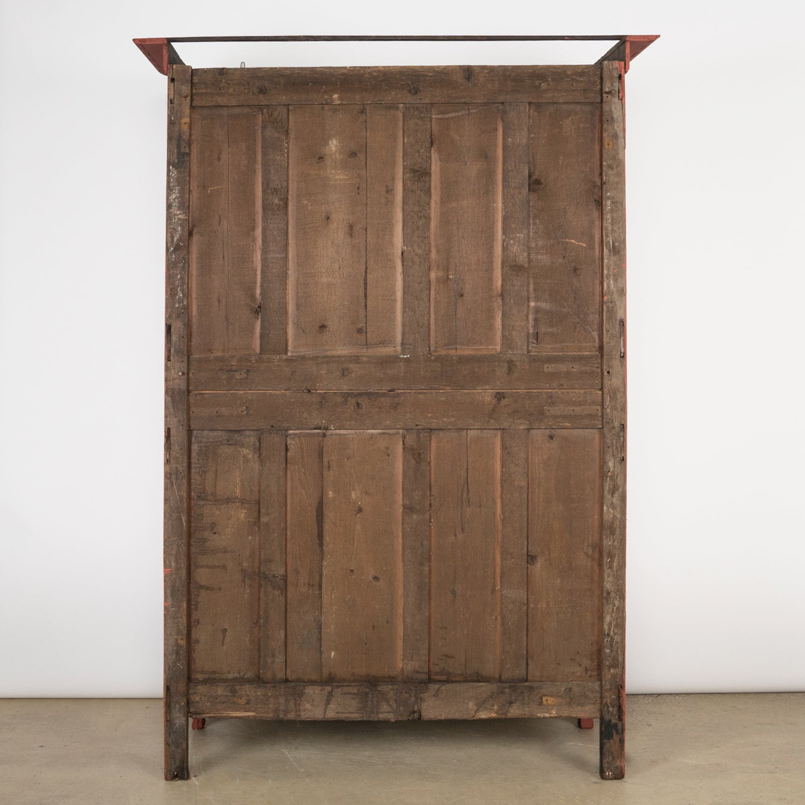 Backside of an antique French marriage armoire, painted in vibrant brick red.