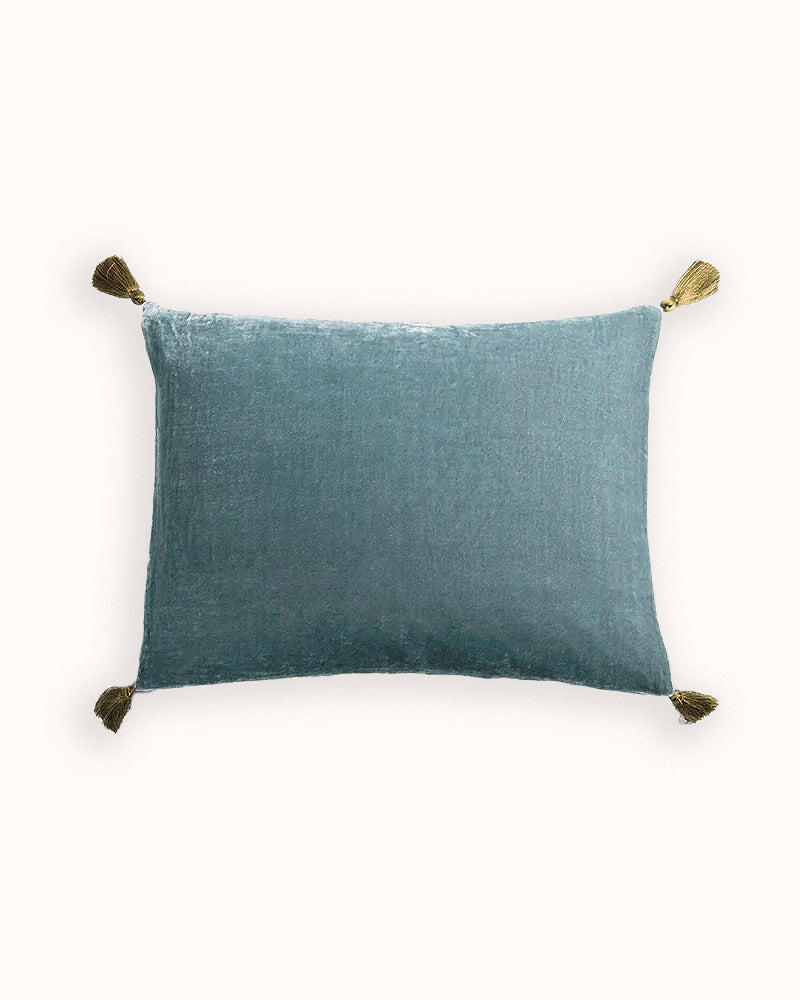 Grey-blue velvet cushion with olive green tassels on a light background, by Monde Sauvage available via Wildschut Antiques.