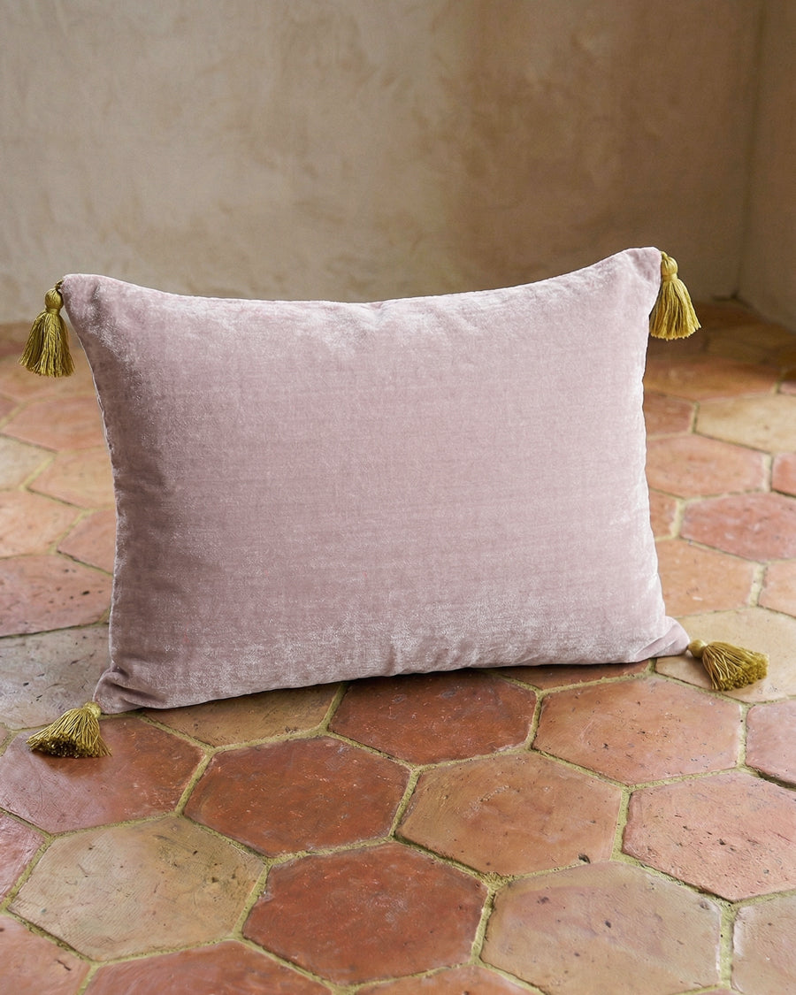 Soft light pink velvet pillow with yellow tassels on a terracotta floor. By Monde Sauvage, available via Wildschut Antiques.