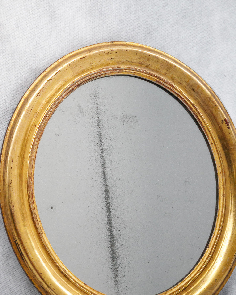 Close-up of a small antique gold oval mirror with foxed glass, available via Wildschut Antiques