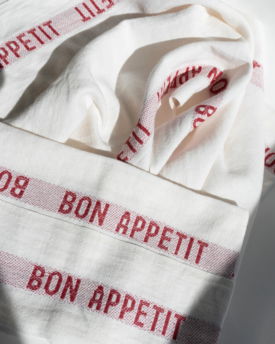 White linen towels with red 'Bon Appetit' text pattern, by Charvet Editions available via Wildschut Antiques.