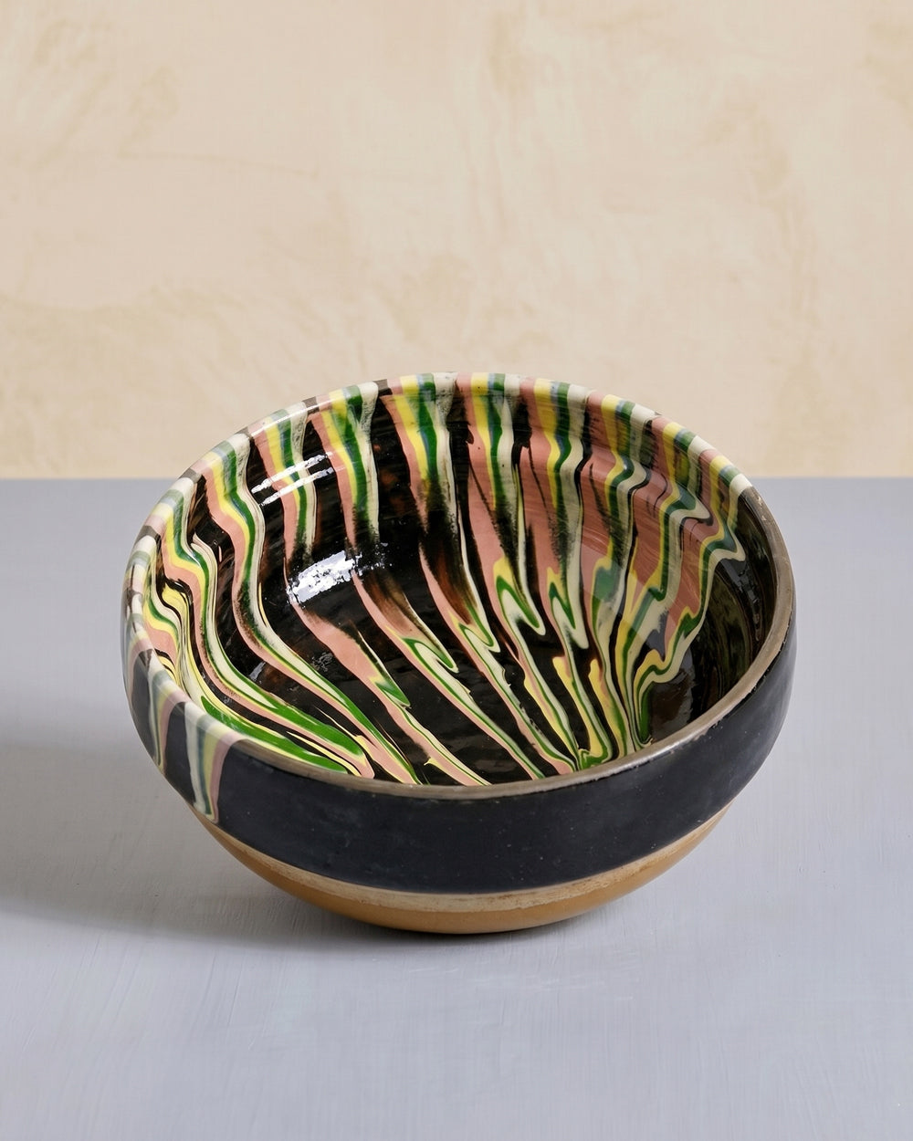 Vintage black ceramic bowl with marble-pattern interior displayed on a grey surface, available at Wildschut Antiques.