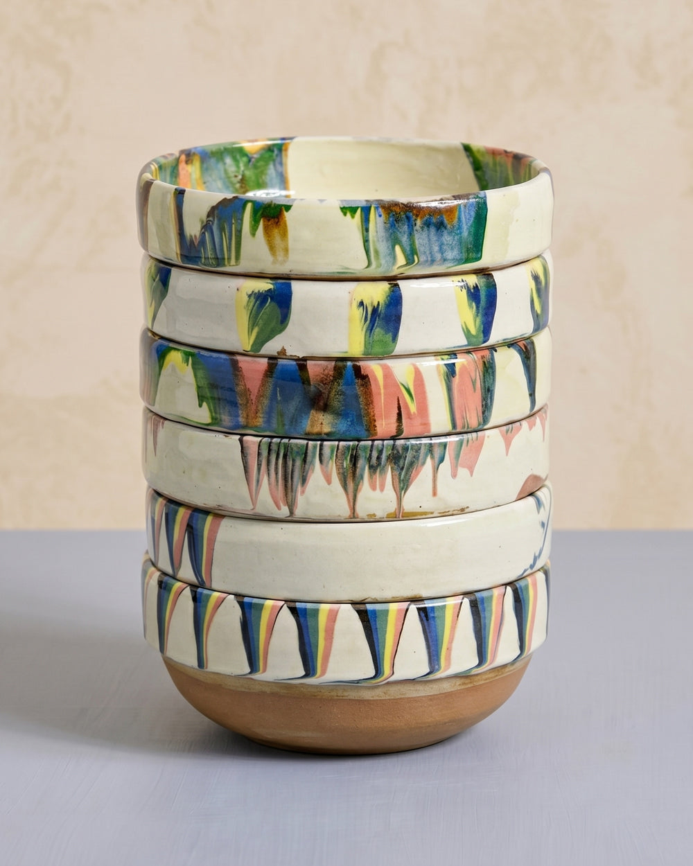Stack of colorful ceramic bowls on a neutral background