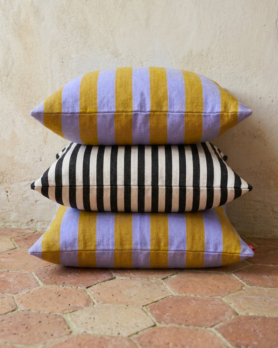 Stack of colorful striped pillows on a terracotta tiled floor.