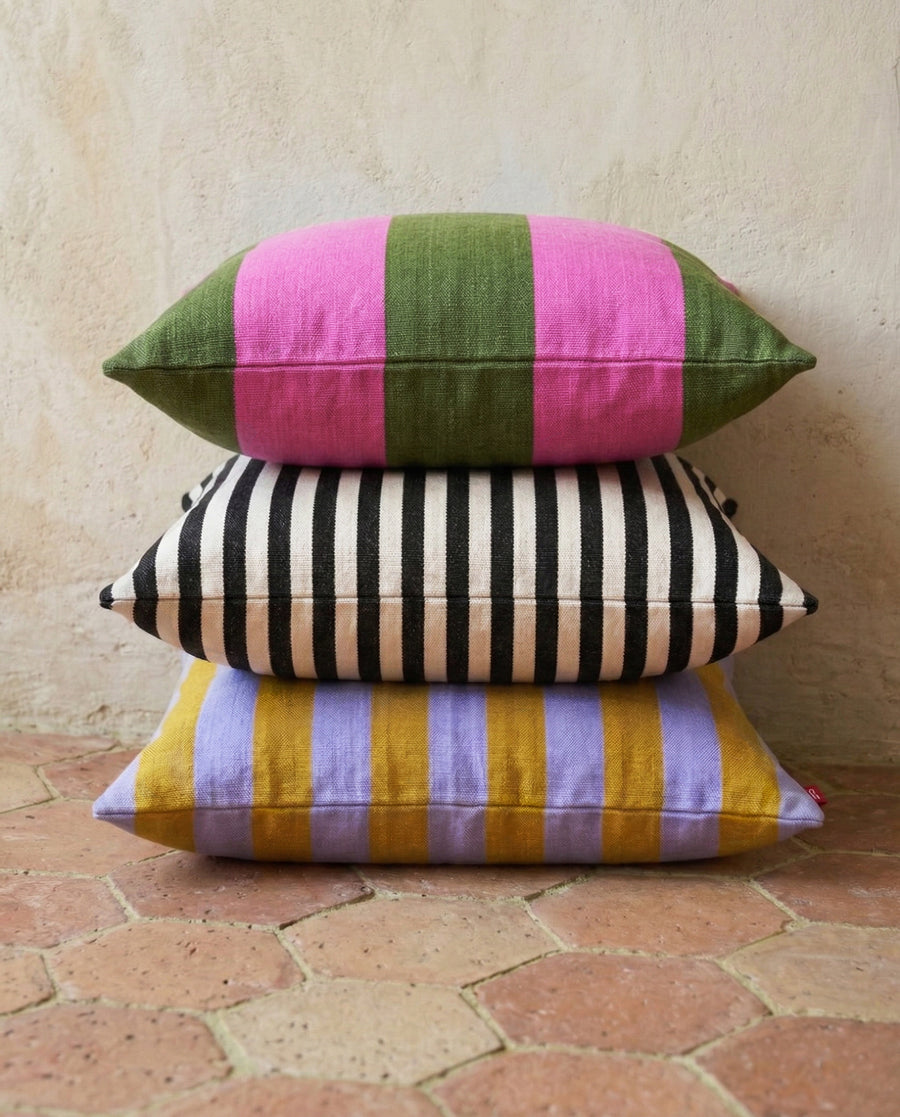 Stack of colorful striped pillows on a terracotta tiled floor.