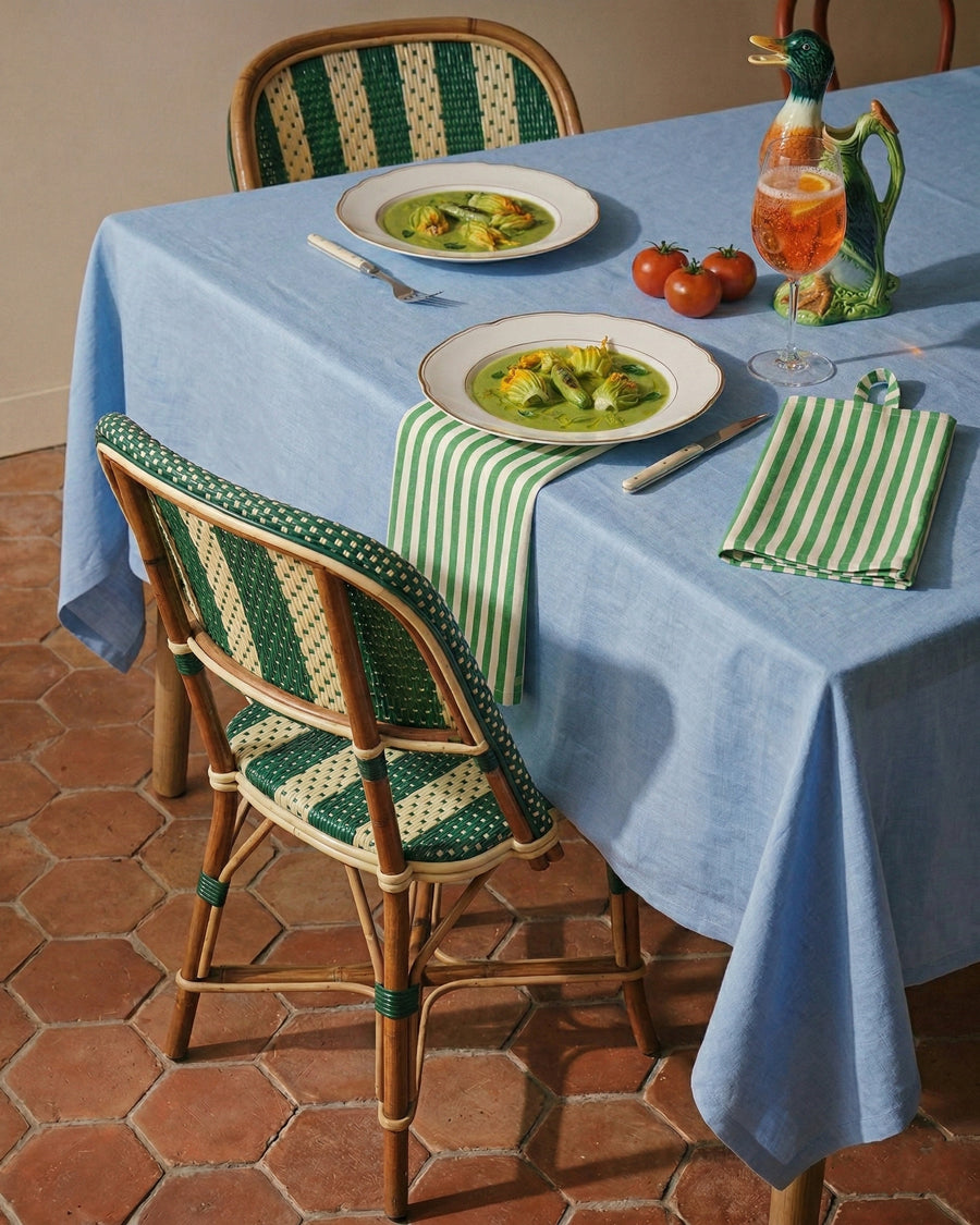 Dining table set with plates of food, tomatoes, and a vintage St. Clement Ceramic Duck Pitcher on a blue tablecloth. Decorative items available via Wildschut Antiques.
