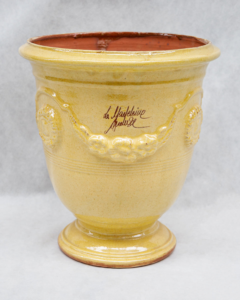 Yellow ceramic French Anduze pot with decorative elements and a signature on a white background available at Wildschut Antiques