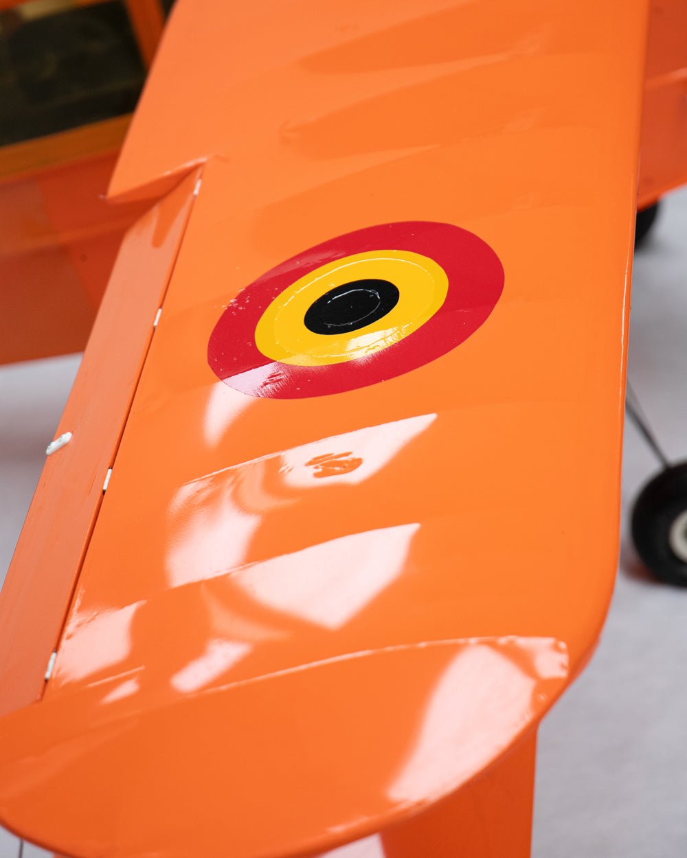 Close-up of an orange aircraft wing with a red, yellow, and black roundel emblem near the center.