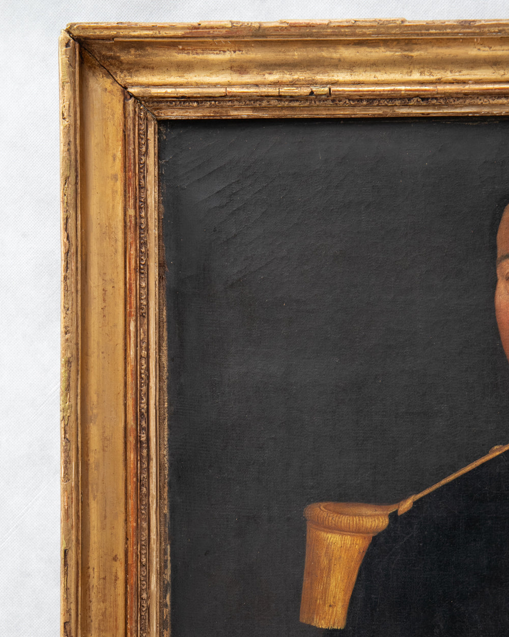 Close-up detail of a framed portrait painting showing part of a person's face and dark clothing, against a black background, with an ornate gold-toned frame. Close-up of an antique portrait of a French Military Man, ca, 1850 - 1870, available via Wildschut Antiques.