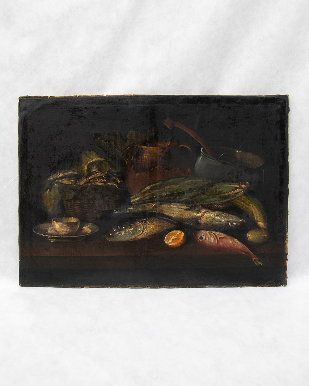 A rectangular still life oil painting depicting fish, vegetables, and kitchenware on a dark background, shown against a light surface. Belonging to a Pair of Neapolitan Fish Still Lifes, 19th Century, available via Wildschut Antiques.
