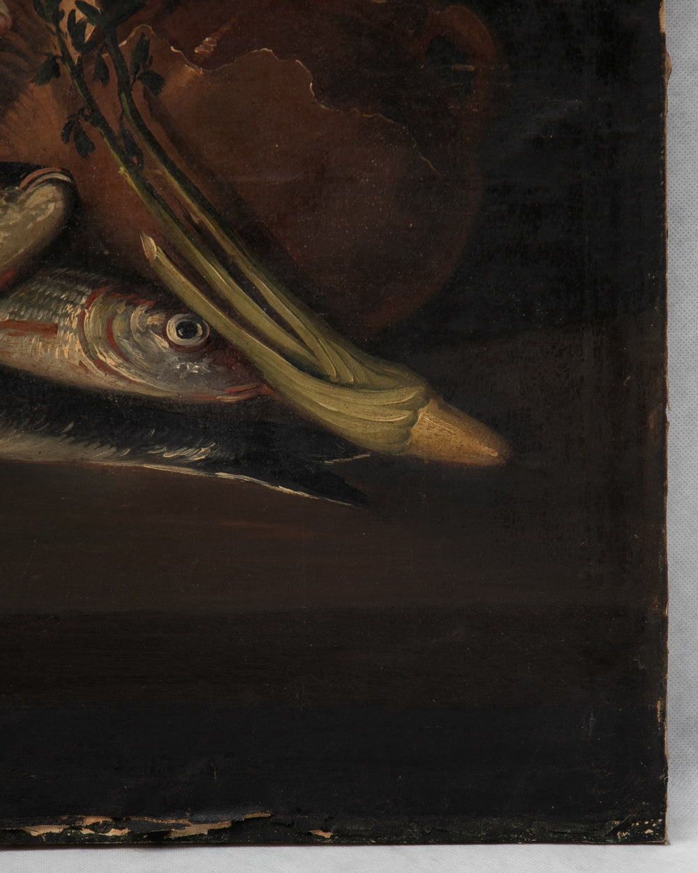 A close-up detail of a dark still-life painting showing part of a fish, green leaves, and a brown vessel against a very dark background.