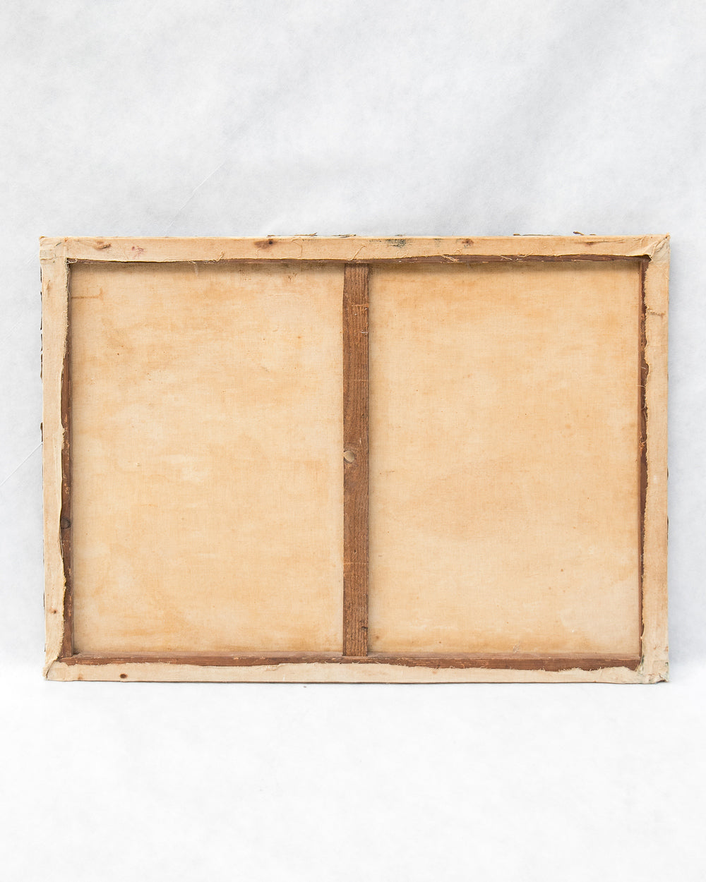 The back of a square canvas print showing the wooden frame and canvas board construction, photographed from above on a light gray marble surface.