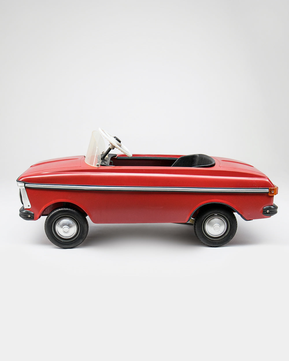 A vintage-style red toy car Moskvich with a white convertible top, black interior, and black wheels, photographed from the side against a light gray studio background. Available via Wildschut Antiques.